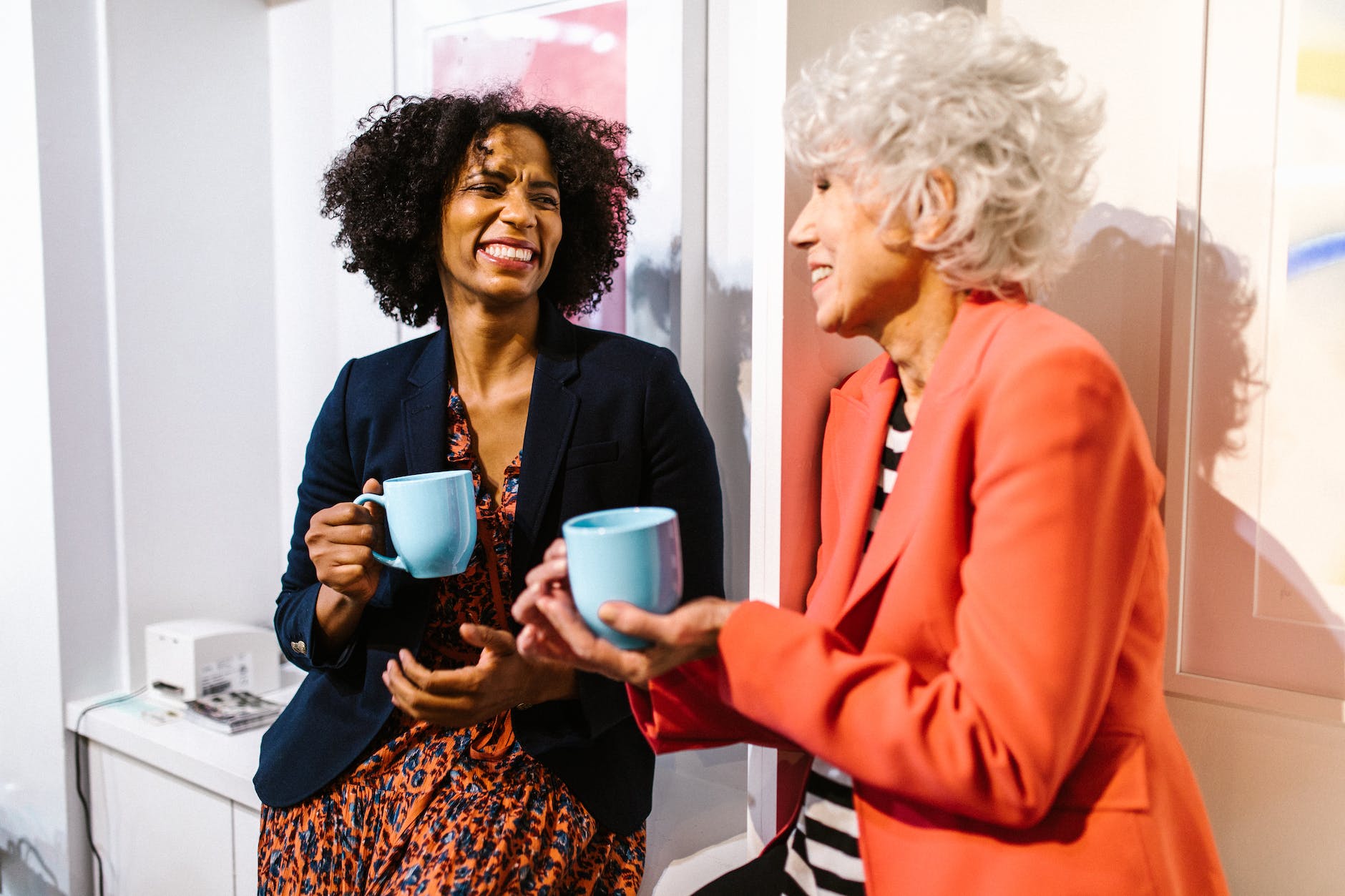 woman in orange blazer holding blue ceramic mug